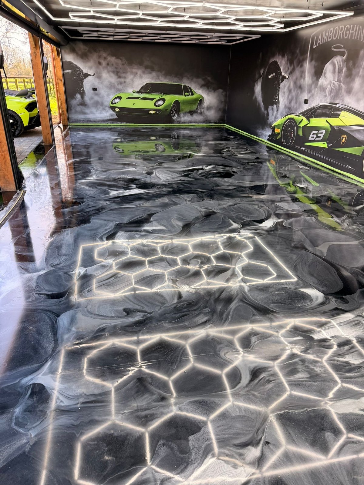 Modern garage interior with lime green sports cars, wet epoxy floor with water refraction patterns, and Lamborghini branding on walls